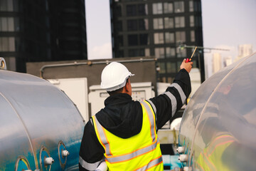 Industrial engineer wearing green safety jacket holding walkie talkie working about HVAC system