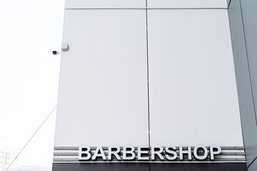 A barbershop sign, in a rectangular fixture, hangs on the building facade