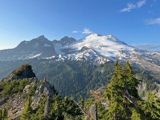 Person sitting on edge of cliff looking out on the mountains