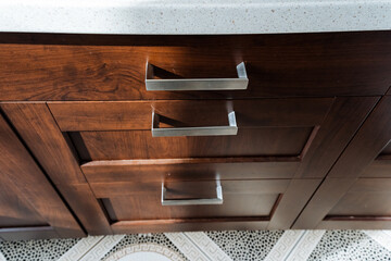 Close up of hardwood cabinet with stainless steel handles