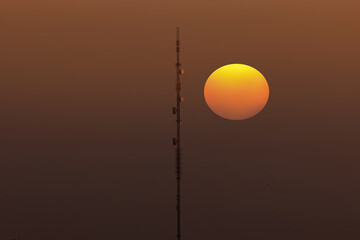 Antenna tower of telecommunication and Phone base station with TV and wireless internet antennas at sunset