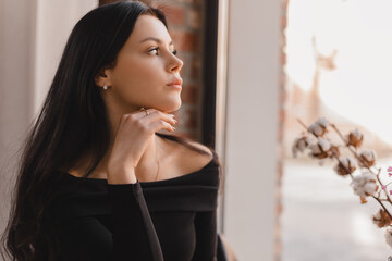 Brunette sensual teen woman sitting in cafe and look outdoors window, she dreaming and think about something. Brunette girl hold her head.
