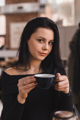 Thoughtful brunette teen woman drinking coffee in cafe, lifestyle, coffee, communication and local business, unaltered. Sensual woman look at camera.