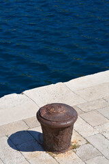Naklejka premium Rusted iron mooring post for boats on a stone pier