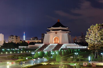 Night scenery of Chiang Kai-Shek Memorial Hall by Liberty Square, a landmark and tourist attraction in Taipei, Taiwan, with the famous 101 Tower standing among high-rise buildings in the background