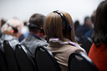 People wearing translation headphones at an international conference, listening to translation on...