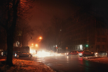 Street fog in the city at the intersection with cars in winter, red tinting