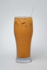 Tall glass of iced Thai tea, captured in an image with a white backdrop.