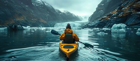 A person in a yellow kayak paddling through the water. - obrazy, fototapety, plakaty