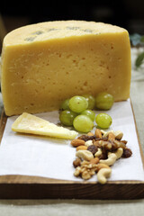 bodegón de queso en tabla de cortar con frutos secos y uvas