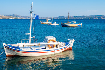 Traditional Greek fishing boats on blue sea in Adamas port bay, Milos island, Cyclades, Greece - 749448900
