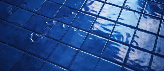 A dark blue tiled floor with lighter blue tiles in a decorative pattern, reflecting water on its surface. The tiles are neatly arranged, creating a visually striking and calming effect.