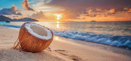 Noix de coco sur une plage déserte tropicale sans personne avec un coucher de soleil. - obrazy, fototapety, plakaty