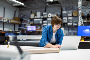 Woman using laptop at printing factory 
