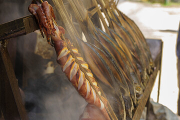 Skewers of squid and fish cooked over an open fire, a delicious and affordable meal enjoyed by...
