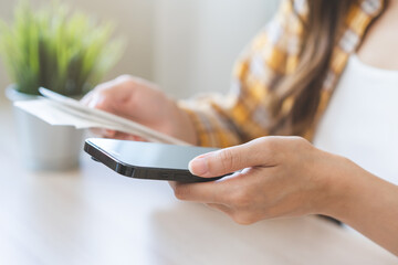 Bill pay concept. Online internet banking asian young woman hand holding receipt paper, using mobile smart phone with calculator apps for calculate expenses to pay of monthly. Technology of financial.