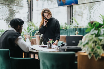 Business professionals engaged in a meeting at a cafe with laptops and documents.