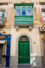 Facade of a typical house with balconies closed by typical Malta windows and doors