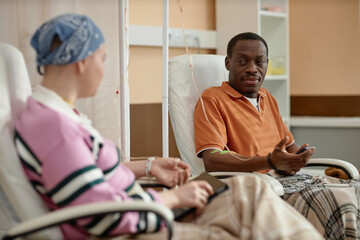 Portrait of Black adult man talking to another patient during chemotherapy treatment in clinic