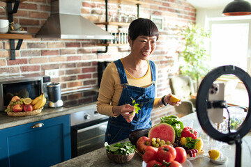 Female food blogger recording cooking vlog in a home kitchen