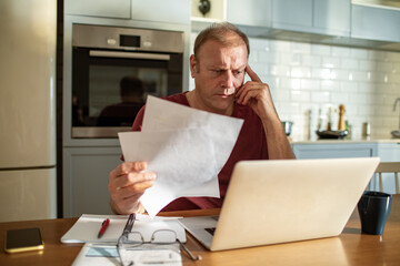 Stressed man going over bills at home