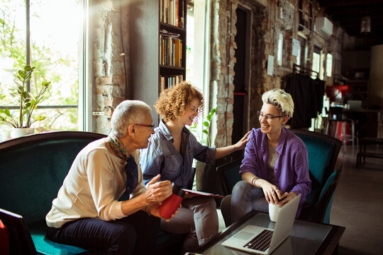 Group of diverse women laughing and collaborating in a creative office space