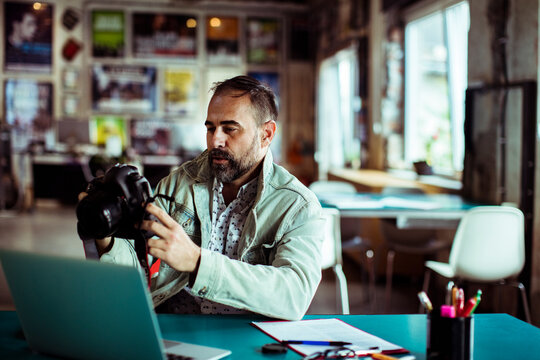 Photographer reviewing pictures on digital camera in a modern office