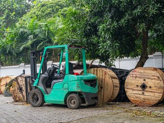 A green forklift parked in front of a series of wire rolls
