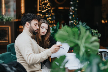 Serious young couple working together in a cafe with a cozy Christmas atmosphere.