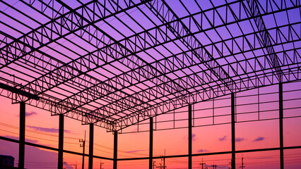 Silhouette of incomplete factory building structure with curve metal roof beam outline and column...