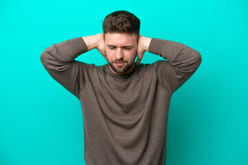 Fototapeta na wymiar Young caucasian man isolated on blue background frustrated and covering ears