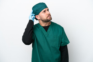 Surgeon in green uniform isolated on white background having doubts and with confuse face expression