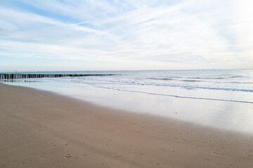 Fototapeta na wymiar lonely beach with waves and sky in zeeland, the netherlands