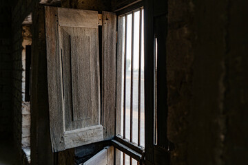 Vintage aged opened wooden window inside concrete house with coming through metal barrier on window base.