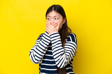 Young Chinese woman isolated on yellow background covering mouth and looking to the side