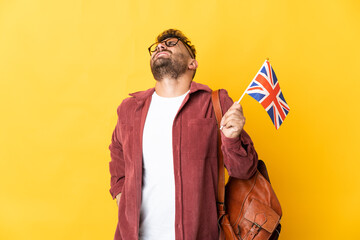 Caucasian man holding an United Kingdom flag isolated on yellow background suffering from backache for having made an effort