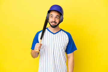 Young caucasian man playing baseball isolated on yellow background thinking an idea while looking up