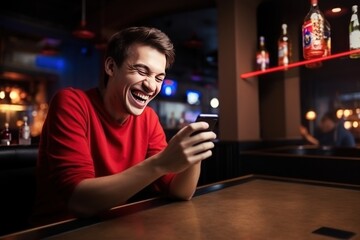Portrait of a young man laughing while using mobile phone in bar. Online Casino and Betting Concept with Copy Space. Gambling Concept.