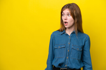 Young English woman isolated on yellow background doing surprise gesture while looking to the side