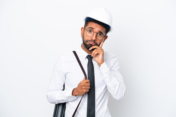 Young architect Brazilian man with helmet and holding blueprints isolated on white background thinking an idea
