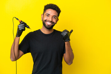 Tattoo artist man Brazilian man isolated on yellow background pointing to the side to present a...