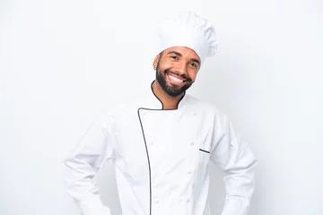 Fotobehang Young Brazilian chef man isolated on white background posing with arms at hip and smiling © luismolinero