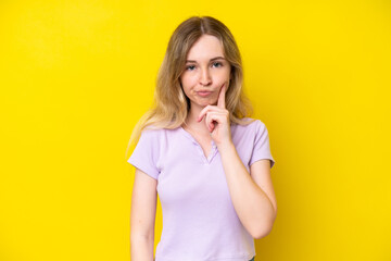 Blonde English young girl isolated on yellow background and thinking