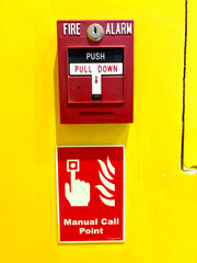 Red fire alarm switch on a vibrant yellow wall with instructions