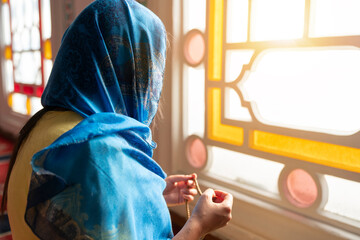 Muslim woman prays rosary. Muslim woman in traditional attire with hijab and rosary praying in a mosque