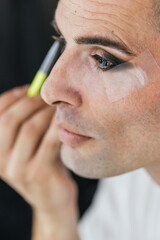 Close up view of a man doing his makeup.