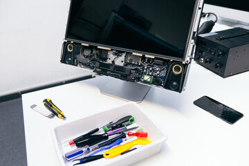 Laptop repair workspace with open device and various tools.