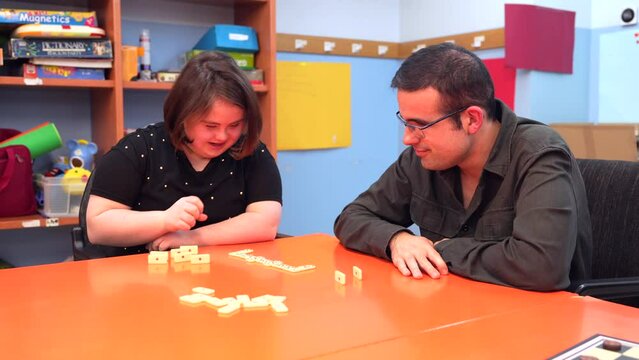 Woman with down syndrome and disabled man playing board games in a day center