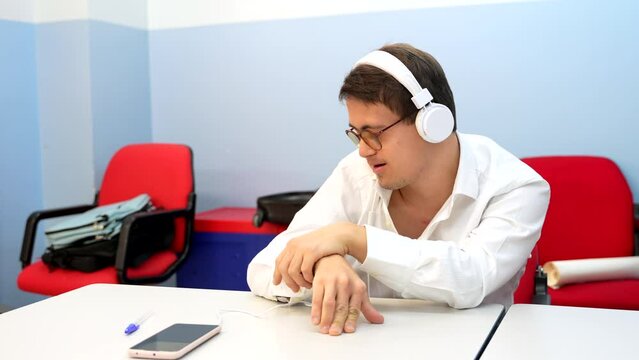 Man with down syndrome listening to music with phones sitting indoors