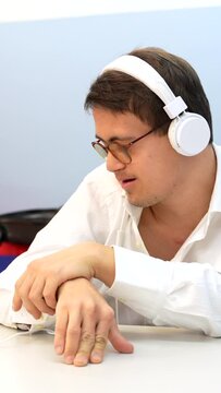 Man with down syndrome listening to music with phones sitting indoors